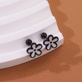 Close-up of flower stud earrings with black and white petals on a tiered display stand - Black & White Combo