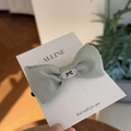 Close-up of sage green fabric bow hair clip with central oval button on display card - Avocado Green Single Bowknot Hair Tie