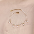 Elegant gold pearl bracelet featuring moon star charms and S.steel logo tag on silk - Pearl White Star Moon