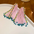 Detail view of pink beaded fringe earrings on a white ceramic plate and wooden background - Soft Pink Glass Seed Bead Tassel (93# Silver Needle)