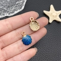 Golden shell charms with blue enamel finish displayed on hand for DIY jewelry making - Drip Oil Blue Ocean Starfish (13x18mm)