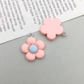Detail of pink resin flower pendants with metal loops on a white vintage paper background - Pink Resin Flower