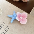 Dettaglio del fermaglio con stella marina e fiore con perla su sfondo in tela beige - Stile Stella Marina Blu