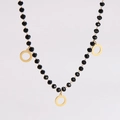Détail d'un collier minimaliste avec perles facettées noires et trois pendentifs dorés - Collier / Noir/Or