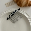 Close-up of a marble patterned hair comb with metal teeth on a white plate - Cow Print