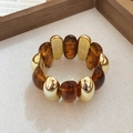 Close-up of gold metal beads and dark amber resin beads on an elastic acrylic bracelet - Dark Coffee