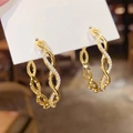 Close-up of golden twist rope hoop earrings with pavé set white zircon stones - Gold