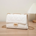 Quilted white crossbody bag with gold chain strap and turn-lock closure on wooden table - Classic Quilted Lock Style / White