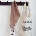 Brown tassel scarf with wavy edges hanging on a beige canvas tote bag with text - Orange Pink