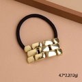 Elastic hair tie featuring a gold textured geometric metal buckle with sleek black band - Gold Watch Band Style