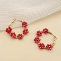 Detailed close-up of handmade gold hoop earrings with red crystal beaded flowers - Red