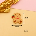 Detail view of a 21mm brown bear charm with a red bow and cherry on a pink background - Brown Cherry Bear