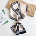 Elegant beige skinny scarf with black and white geometric border on a wooden tray - Woven Chain Black