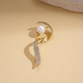 Macro shot of 14k gold plated pearl brooch with zircon inlay on a beige stone surface - Gold Twisted Shape
