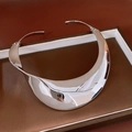 Close-up of polished silver wide curved metal collar necklace on display tray - Twisted Wide Surface Choker / Silver