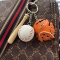 Close-up of mini leather baseball, wooden bat, and glove keychain hanging on a bag - 3.5CM White Ball Orange Yellow Black Strap