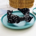 Black fabric headband with white paisley pattern and top knot detail on a plate - Rabbit Ear Paisley / Black