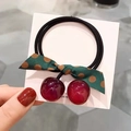 Détail d'un élastique cerise avec breloques en résine rouge et nœud vert à pois - Élastique Cerise / Bordeaux