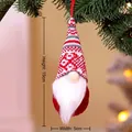 Knitted Christmas gnome ornament in red and grey hanging on a festive tree branch - Style I