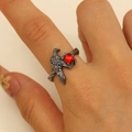 Macro view of raven ring featuring black metal feathers and a faceted red gemstone - Gun Black Crow With Bead Style (7517)