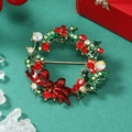 Gros plan sur la broche couronne de Noël avec strass colorés et nœud papillon rouge - Or KC Rouge