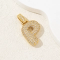 Gold-plated letter P pendant with cubic zirconia inlay on a beige textured surface - Letter P