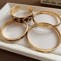 Détail d'un ensemble de bracelets dorés avec un large jonc léopard et trois joncs fins - Combinaison Léopard Doré (Ensemble de 4 pièces)