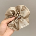 Macro shot of champagne satin scrunchie showing glossy pleated silk texture - Khaki