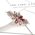Fermaglio a farfalla dorato con cristalli rosa e strass trasparenti su sfondo bianco - Rosa