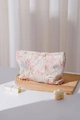 Close-up of pink embossed floral texture fabric and brand label on a makeup bag - Large / Pink Floral