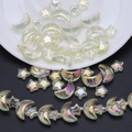Detailed view of iridescent moon and star glass beads set on a ceramic dish for DIY jewelry - Crystal Yellow
