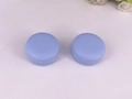 Detail view of two lavender macaron-shaped cosmetic jars on a white floral background - 10 g / Light Blue