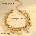Detalle de pulsera dorada de doble capa con colgantes de corazón sobre fondo de piedra - Pulsera Dorada de Doble Capa con Colgante de Corazón y Cuentas