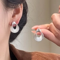 Detail of twisted silver earrings worn by model showing artistic hollow design and gloss - Silver Twisted Round