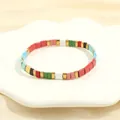Detailed macro view of bohemian colorful Tila tile beads on a ceramic floral tray - Multicolor F-Red Blue Green Pink White Black Gold