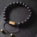 Macro view of matte black lava stone beads and golden metal plate on adjustable bracelet - Lava Stone Braided