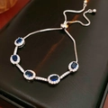 Detailed macro view of adjustable silver bracelet with five oval blue zircons and box chain - Silver-Blue