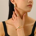 Detail view of mirror finish gold teardrop jewelry set featuring earrings, ring and bangle - Gold Mirror Waterdrop Three-Piece Set / Gold