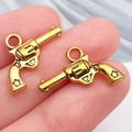 Pendentifs revolvers en métal doré pour bijoux DIY tenus entre deux doigts - Pistolet Revolver (19229) / 14x19mm