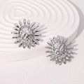 Detailaufnahme der silbernen Sonnenblumen-Ohrringe mit Hammerschlag-Optik auf weißem Ständer - Stahlfarbe