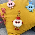 Detailed view of white fluffy monster plush keychain with red hat and gold metal clasp - White