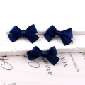 Three navy blue satin ribbon bow hair clips displayed on a white textured pedestal - Navy Blue