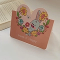 Pink heart-shaped card with cute cartoon rabbit and Keep it Happy text on desk - Cute Rabbit