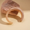 Macro detail of a chunky marble-pattern resin open cuff bracelet on textured stone - Brown