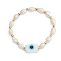 Close-up of freshwater pearl bracelet featuring a rectangular evil eye charm and gold beads - White