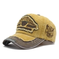 Primer plano de gorra vintage amarilla con visera desgastada y bordado de águila - Amarillo