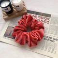 Elegant red velvet scrunchie featuring soft texture and natural pleats on newspaper - Orange Red