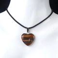 Tiger eye heart pendant necklace featuring a polished stone on a black woven cord - Tiger's Eye