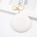 Close-up of a white round folding makeup mirror charm with a golden metal keychain - White