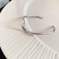 Vista superior de un brazalete abierto plateado pulido en una bandeja blanca con relieve - Plata - Onda Fina